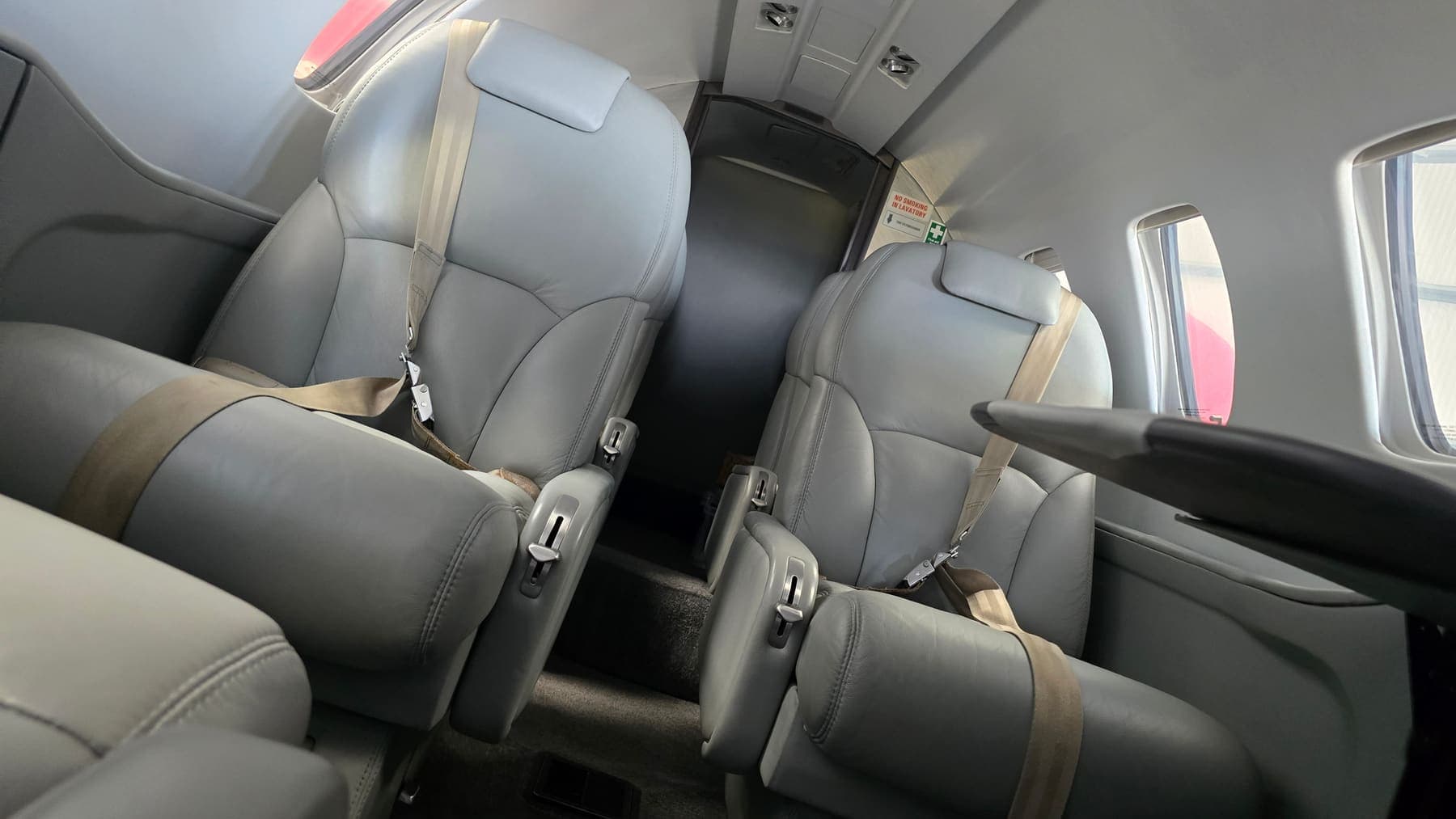 Charter Citation club cabin after an interior clean — grey leather seats and belts ready for the next trip