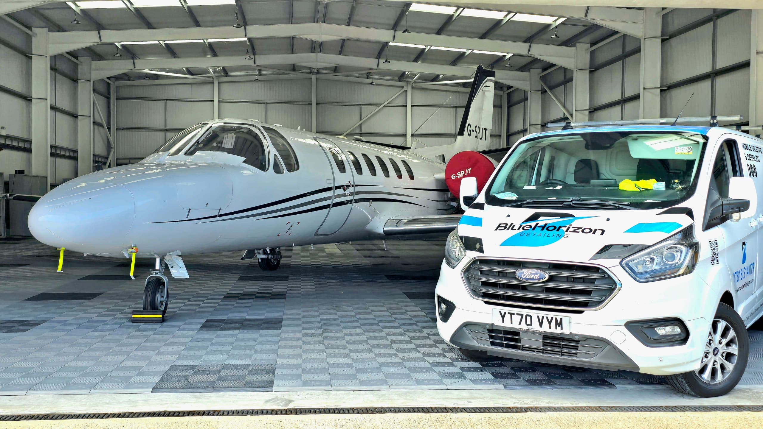 A detailed Citation business jet in the hangar with the Blue Horizon service van alongside