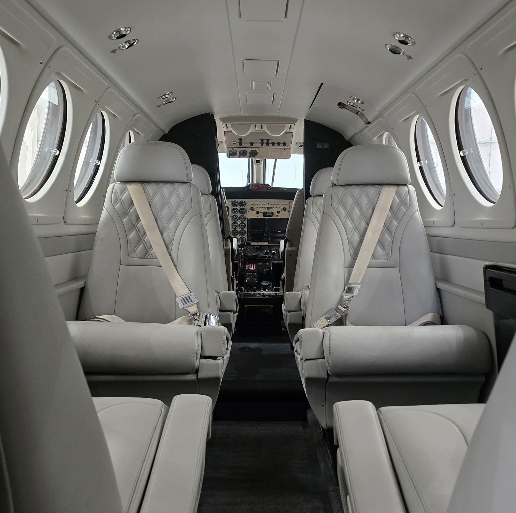 Looking forward through a spotless King Air cabin — cleaned leather club seats, belts and carpet either side of the aisle