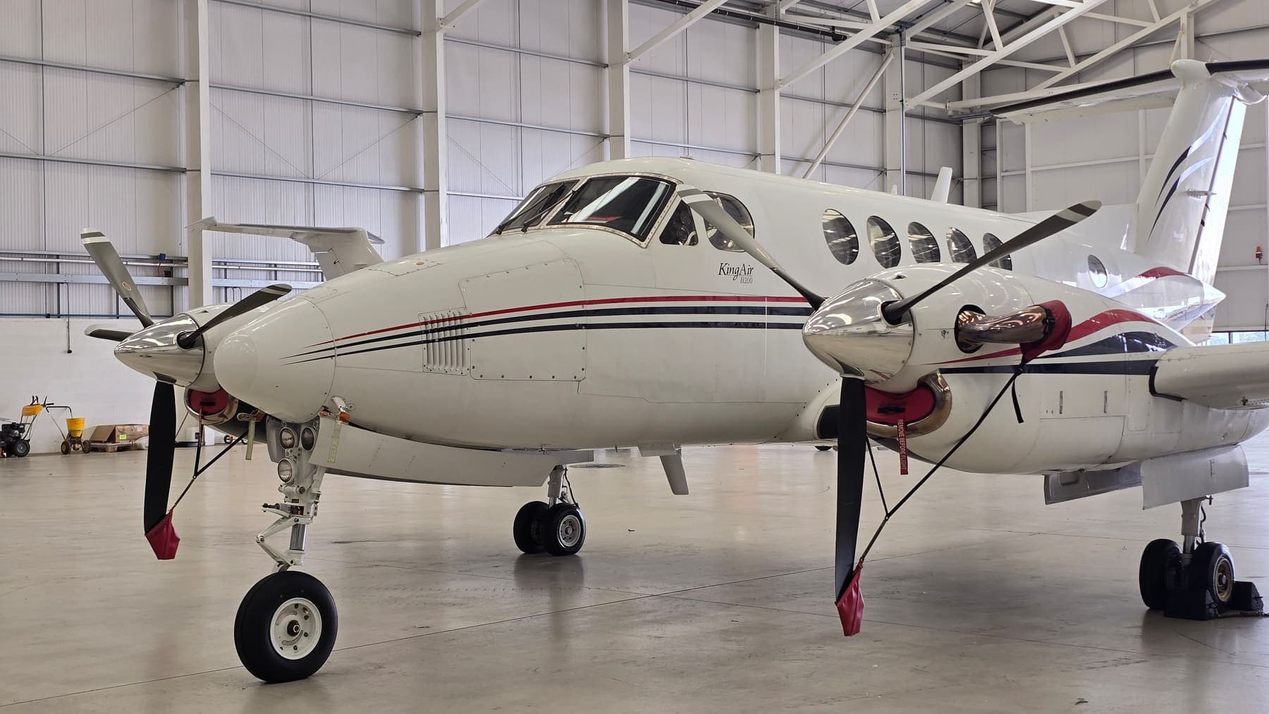 A freshly cleaned Beechcraft King Air B200 turboprop in the hangar, propellers and polished spinners forward