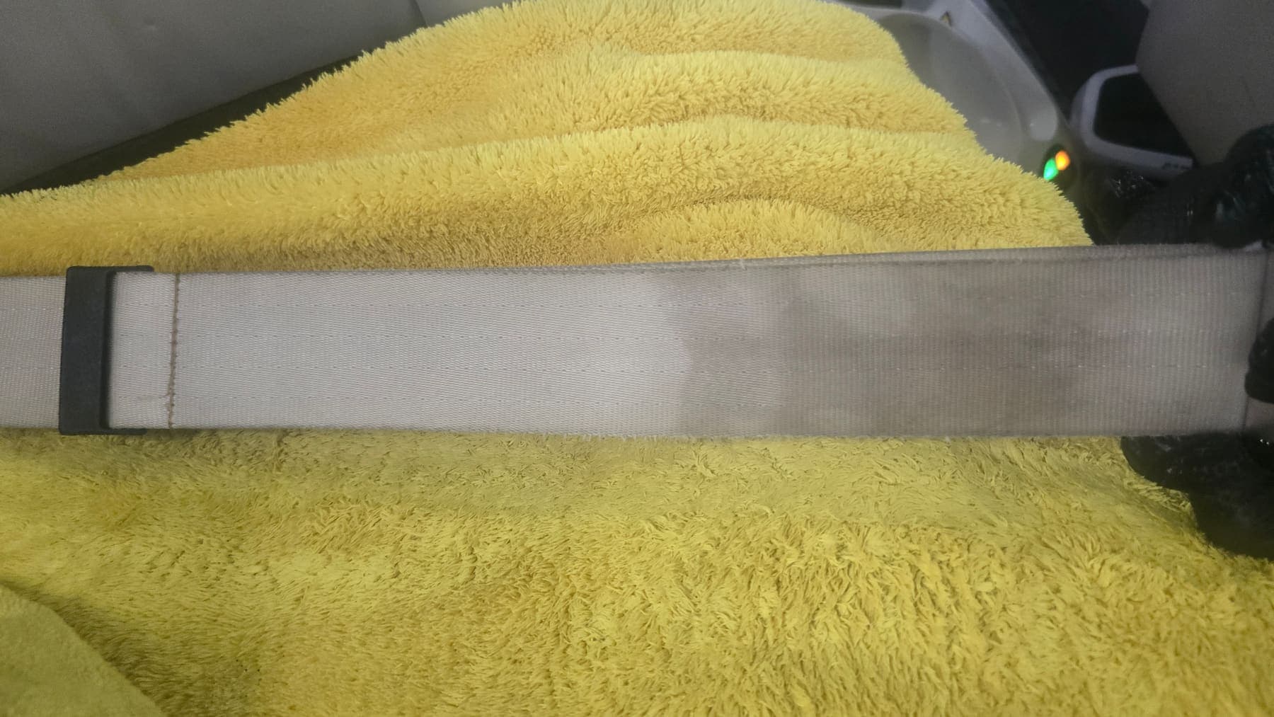 A seat belt mid-deep-clean — one half bright and clean, the other still grey with ingrained soiling