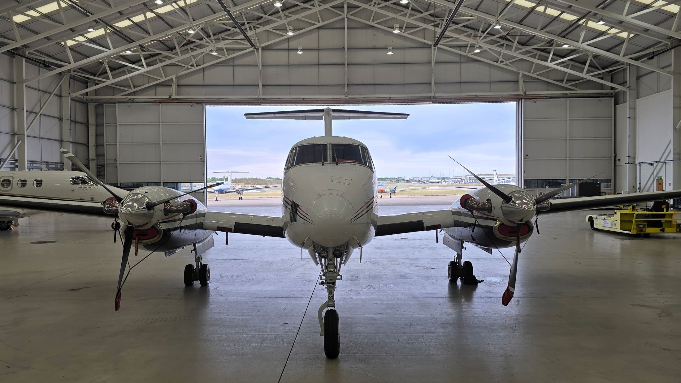 A King Air B200 facing the open hangar doors after a full clean, airfield beyond