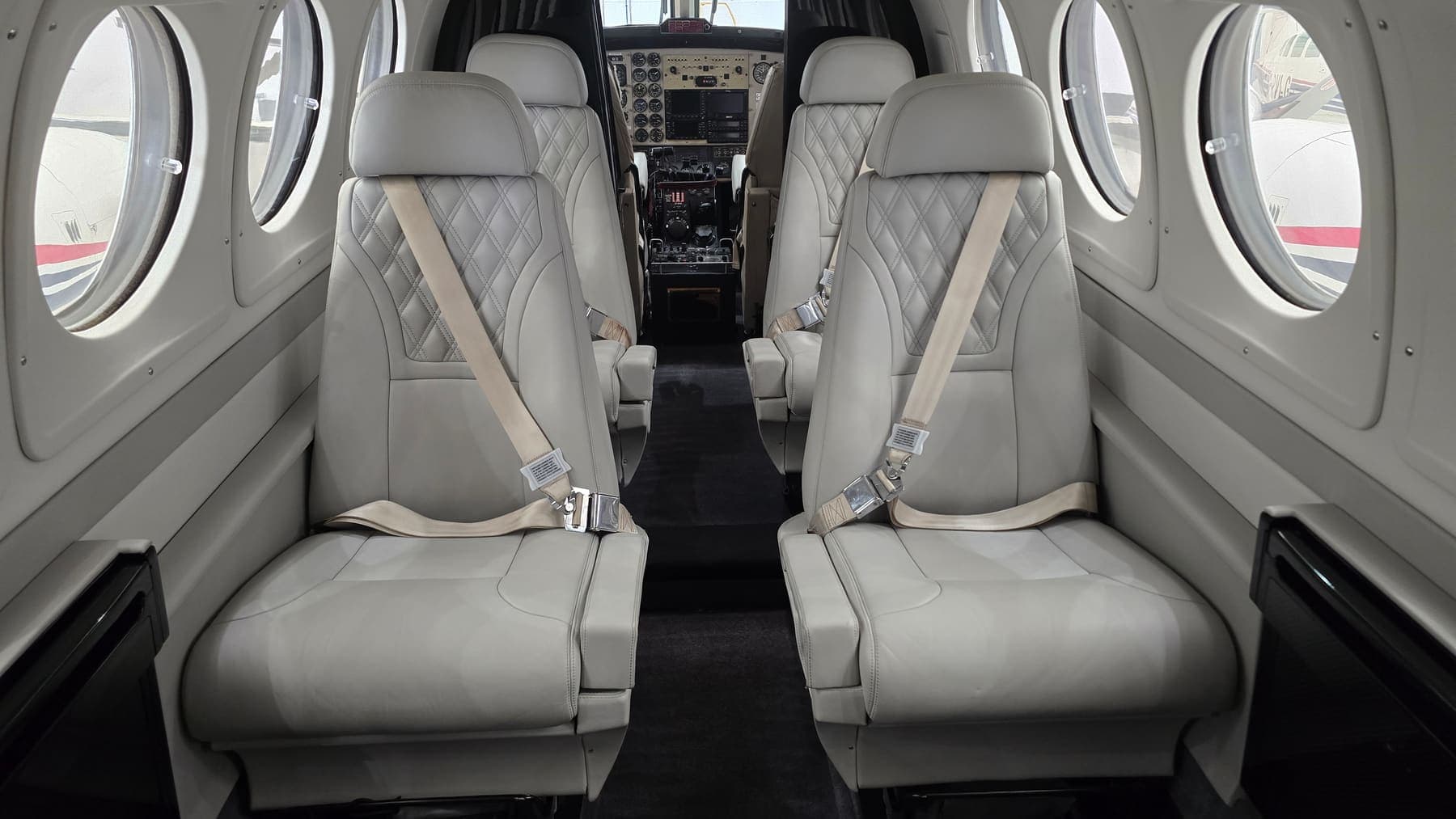 Cleaned and reconditioned quilted leather seats in a King Air cabin, cockpit beyond