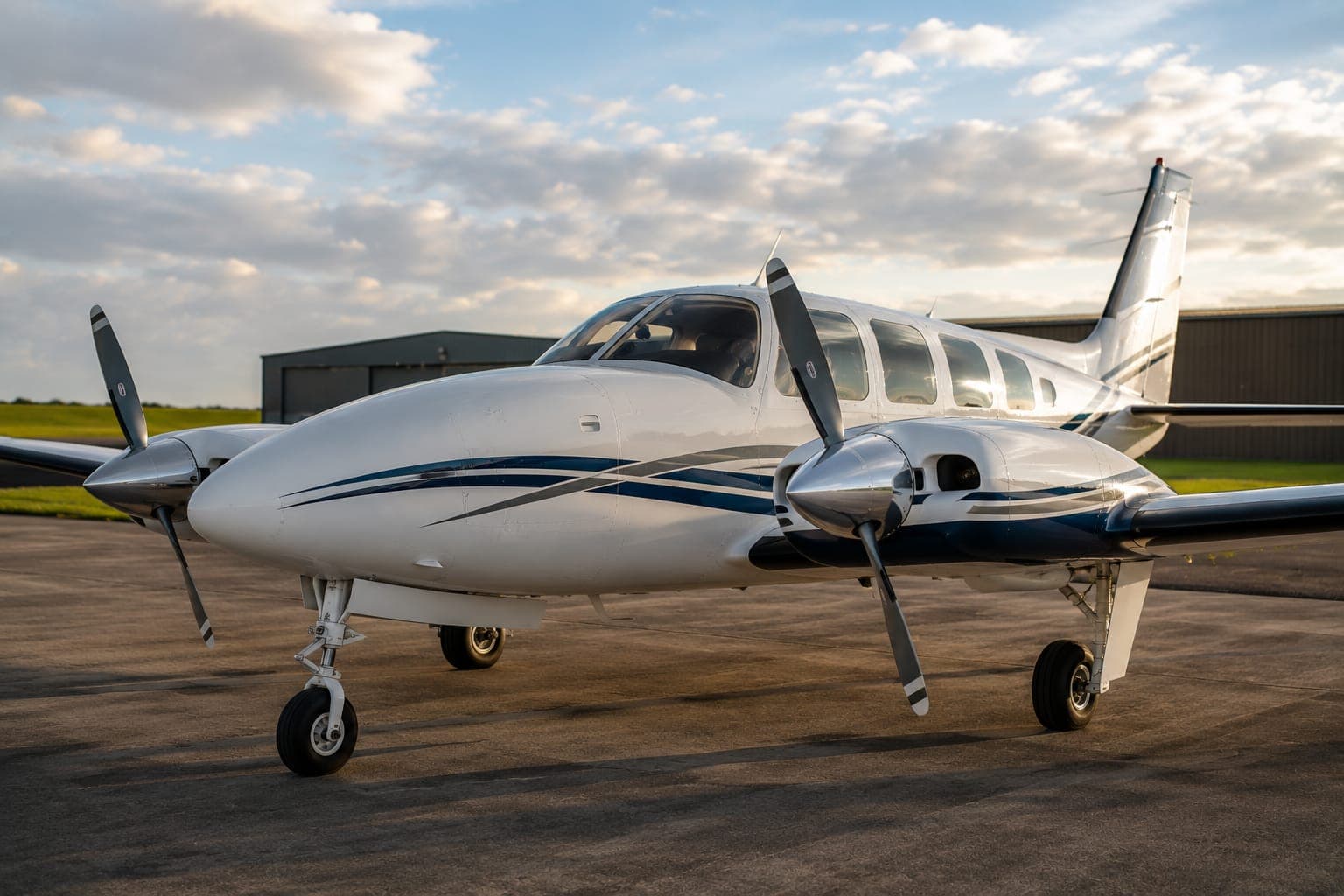 A freshly detailed twin-engine piston aircraft on the apron in golden evening light